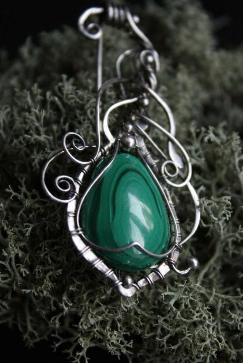 Silver scrollwork around green stone